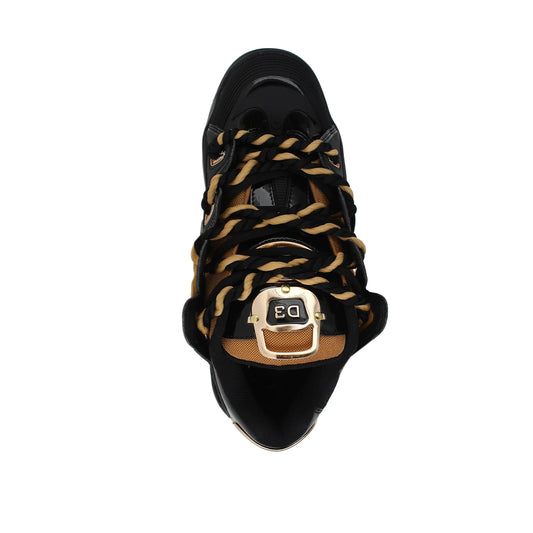 Black sneaker with gold and brown braided laces on a white background