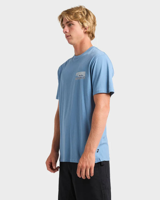 Man wearing a light blue t-shirt with a logo on a white background