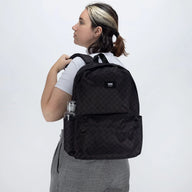 Person wearing a black quilted backpack on a white background