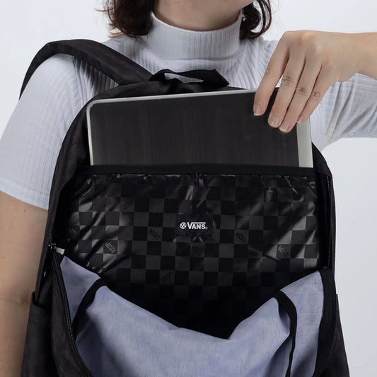 Person opening a black Vans backpack with a laptop inside on a white background