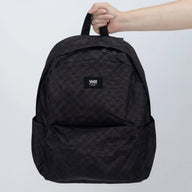 Black backpack with a Vans logo held by a hand on a light gray background