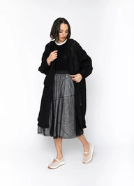 Woman wearing a black coat and gray skirt on a white background
