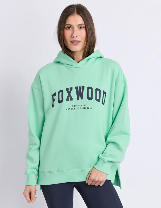 Lady wearing Foxwood Hood in Mint Green with Navy logo and white background