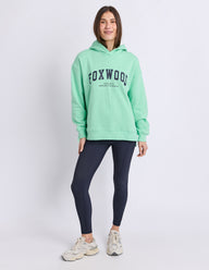 Lady wearing Foxwood Hood in Mint Green with Navy logo and white background