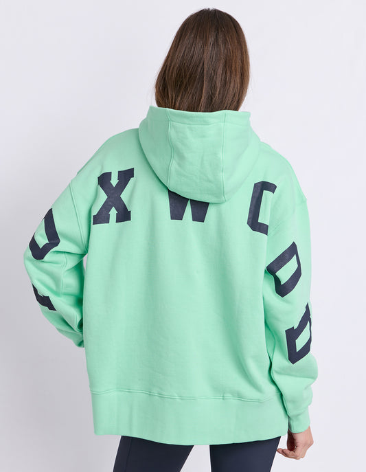Lady wearing Foxwood Hood in Mint Green with Navy logo and white background