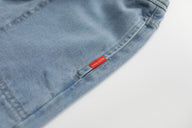 Close-up of a blue denim garment with a red label on a white background