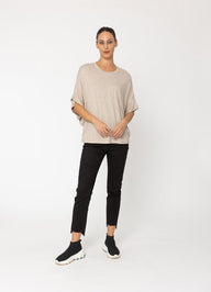 Woman wearing a beige top and black pants on a white background