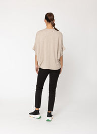 Person wearing a beige oversized shirt and black pants on a white background