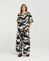 Woman wearing a black and white patterned outfit on a plain background