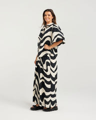 Woman wearing a black and white patterned dress on a white background