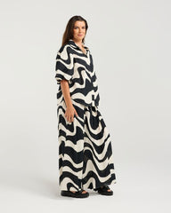 Woman wearing a black and white patterned dress on a white background