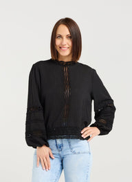 Woman wearing a black sweater and light blue jeans on a white background