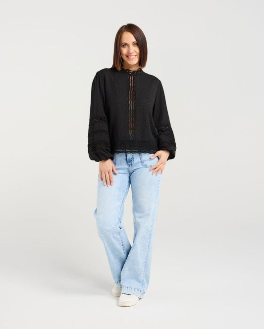 Woman wearing a black sweater and light blue jeans on a white background