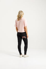 Lady wearing Home-Lee Apartment Pants with pink Bow, Pink Tee, white sneakers and white background
