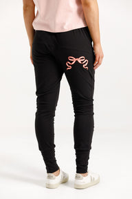 Lady wearing Home-Lee Apartment Pants with pink Bow, white sneakers and white background