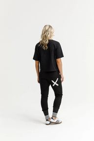 Person wearing a black t-shirt and black jogger pants with white designs on a white background