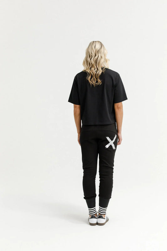 Person wearing a black t-shirt and black pants with a white logo on a white background
