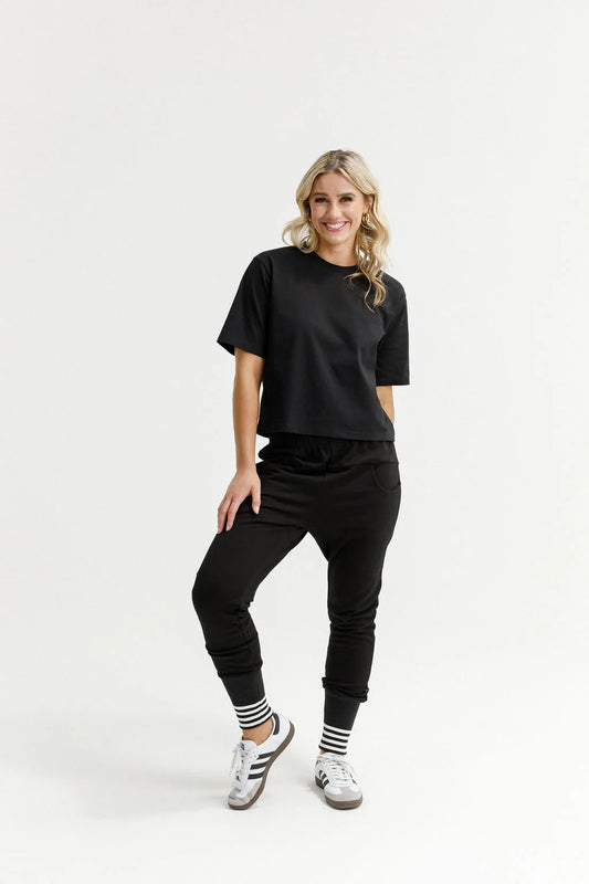 Woman wearing a black outfit with white sneakers on a white background