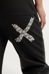 Black pants with a floral 'X' design on a white background