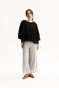 Woman wearing a black top and light gray pants on a white background