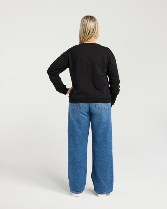 Person wearing a black sweatshirt and blue jeans on a white background