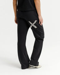 Person wearing black pants with a decorative 'X' design on a white background