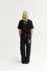 Person wearing black pants with a decorative 'X' design on a white background