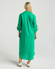 Person wearing a green dress with long sleeves on a plain background