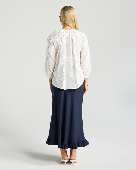 Person wearing a white blouse and navy skirt on a light gray background