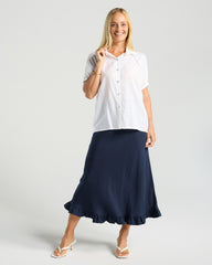 Woman wearing a white blouse and navy skirt on a plain background