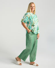 Woman wearing a green floral blouse and green pants on a white background