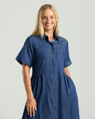 Woman wearing a blue denim dress against a plain background