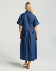 Woman wearing a blue dress standing against a plain background