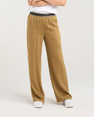 Woman wearing a white t-shirt with 'BLACKSTONE' text and beige pants on a light gray background