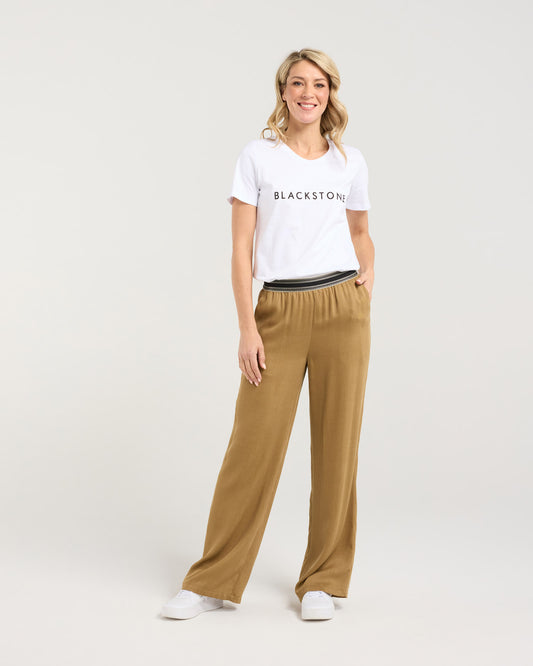 Woman wearing a white 'Blackstone' t-shirt and tan pants on a white background