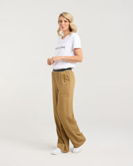 Woman wearing a white t-shirt and beige pants on a plain background