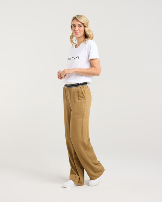 Woman wearing a white t-shirt and beige pants on a plain background