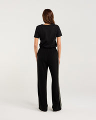 Woman wearing a black outfit with wide-leg pants on a white background