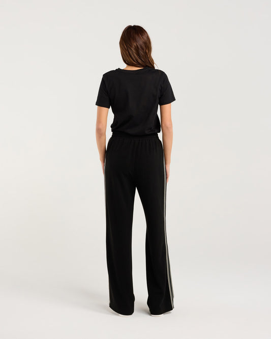 Woman wearing a black outfit with wide-leg pants on a white background