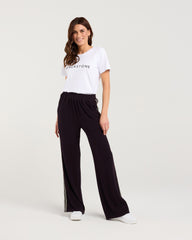 Woman wearing a white t-shirt and black pants on a white background