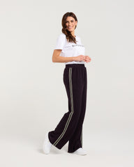 Woman wearing a white t-shirt and black pants with stripes on a white background
