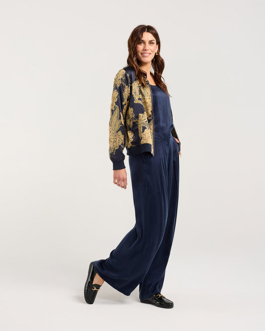 Woman wearing a navy outfit with a patterned jacket on a white background