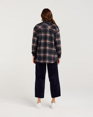 Person wearing a plaid shirt and navy pants on a white background