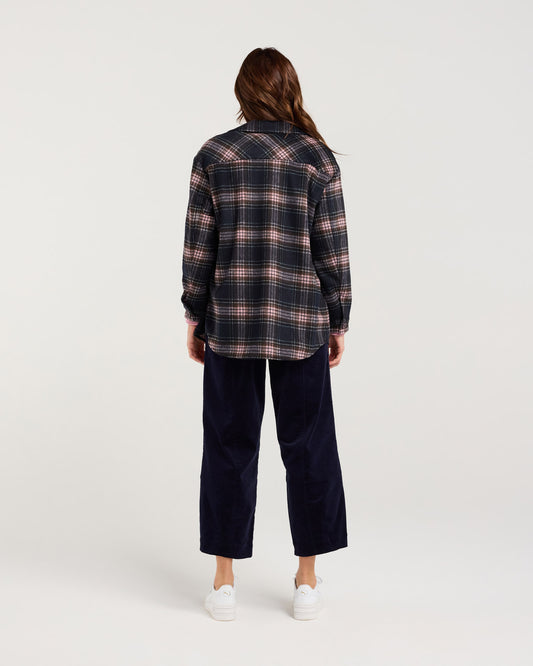 Person wearing a plaid shirt and navy pants on a white background