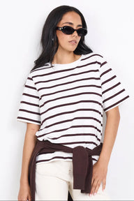 Woman wearing a black and white striped shirt with a brown belt against a white background