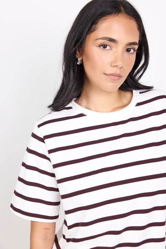 Woman wearing a white t-shirt with brown horizontal stripes against a plain background