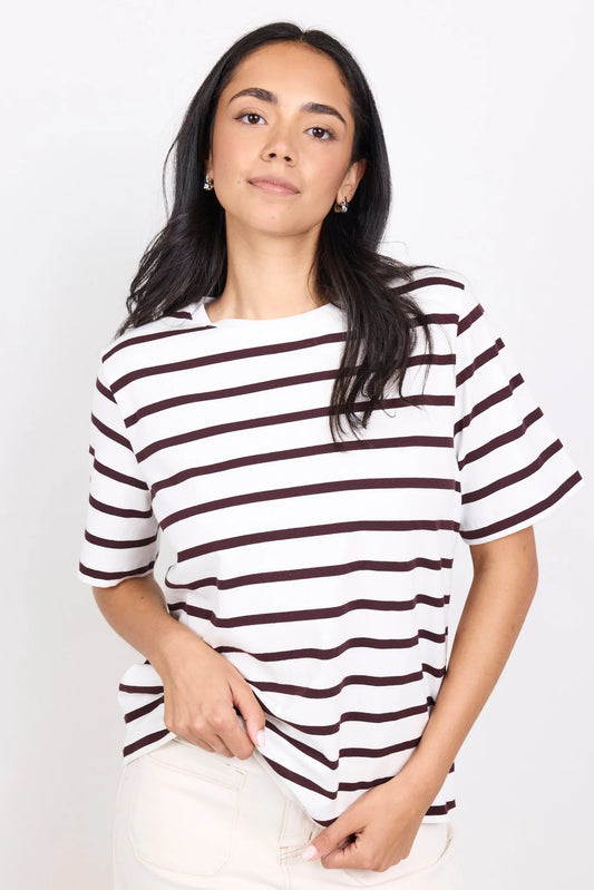 Woman wearing a white and brown striped shirt against a plain background