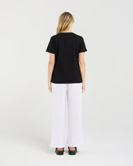 Person wearing a black t-shirt and white pants on a plain background