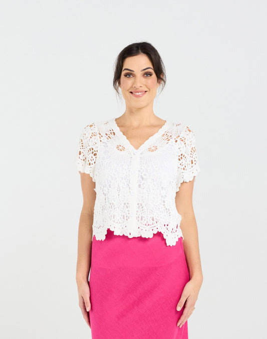Woman wearing a white lace top and pink skirt on a white background