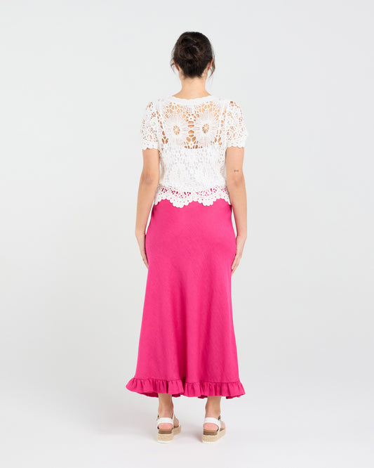 Woman wearing a white lace top and pink skirt on a white background